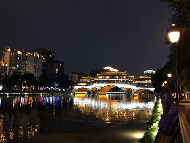 Anshun Bridge floodlit over the Jin River at night, reflected in the water
